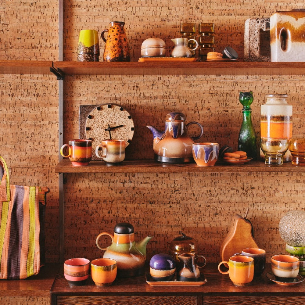 shelves of brightly coloured 70s ceramics from hkliving with jugs and kettles among the cups and mugs