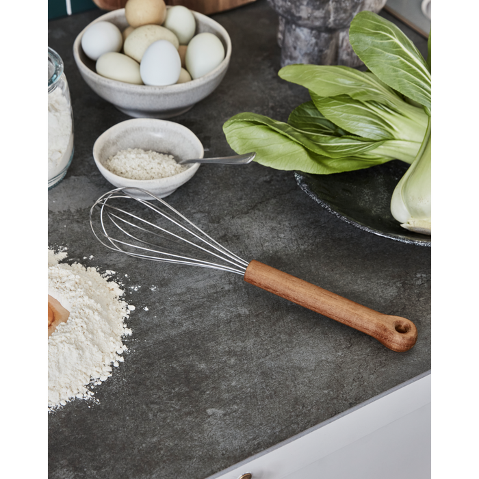 Stainless steel balloon whisk with acacia wood handle from House Doctor – kitchen utensil on countertop
