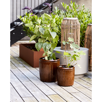 Large and small ribbed outdoor planters on wooden deck with greenery