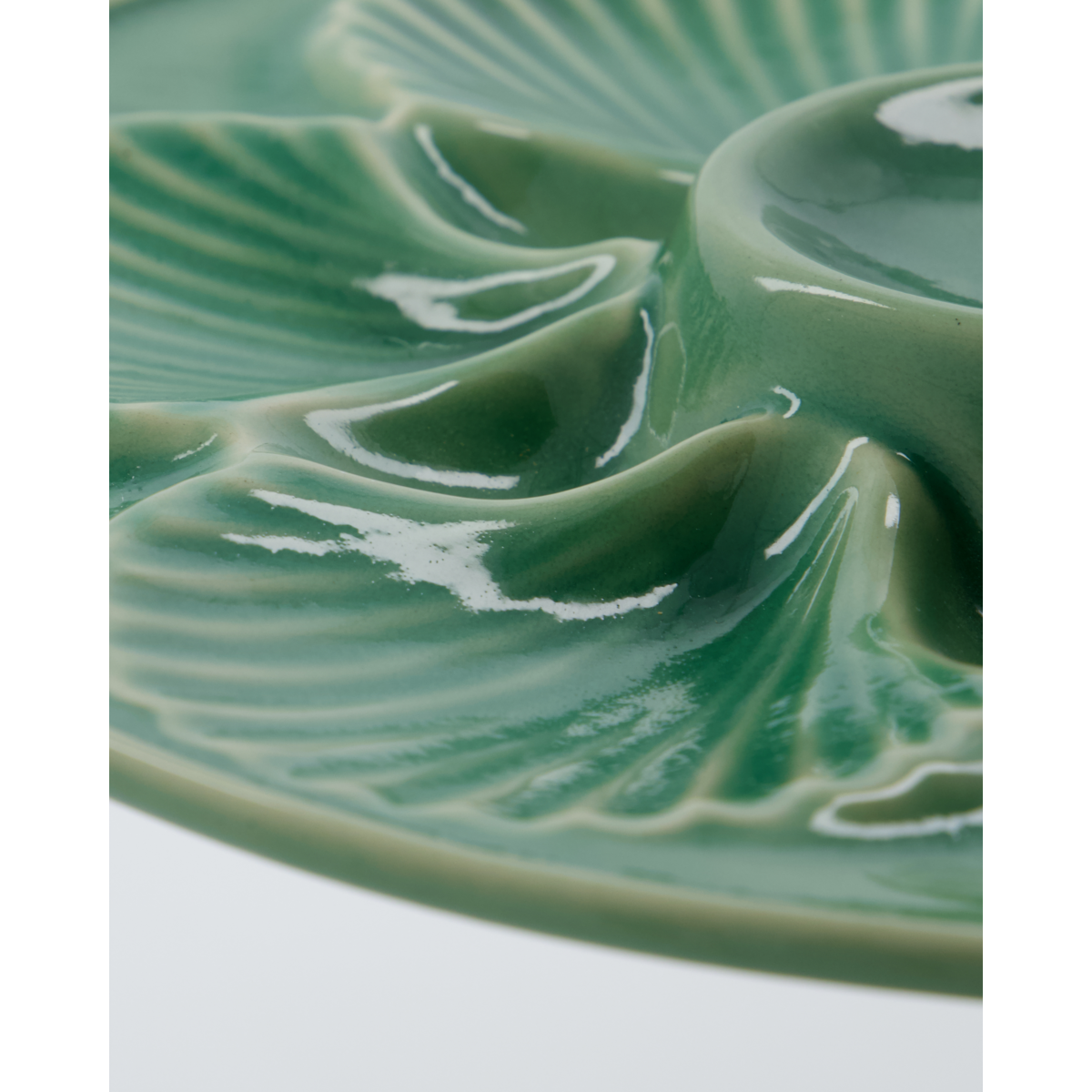 Close-up of handcrafted ceramic detail on green glazed serving plate – modern rustic design