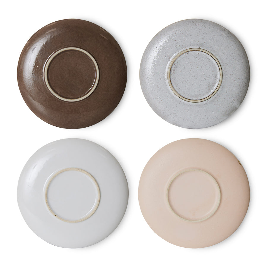 the bottom of all 4 of the saucers in a redish brown, speckled grey, flat grey, and an almost pink hue to the final one