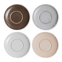 the bottom of all 4 of the saucers in a redish brown, speckled grey, flat grey, and an almost pink hue to the final one