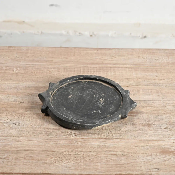 a blackened vintage plate with decoration around the outside and showing signs of age made from repurposed building stone in india perfect as a decorative plate or tray in a nordic style
