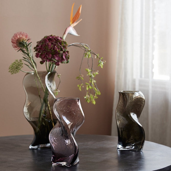 wavey angular vases on a table with flowers and plants
