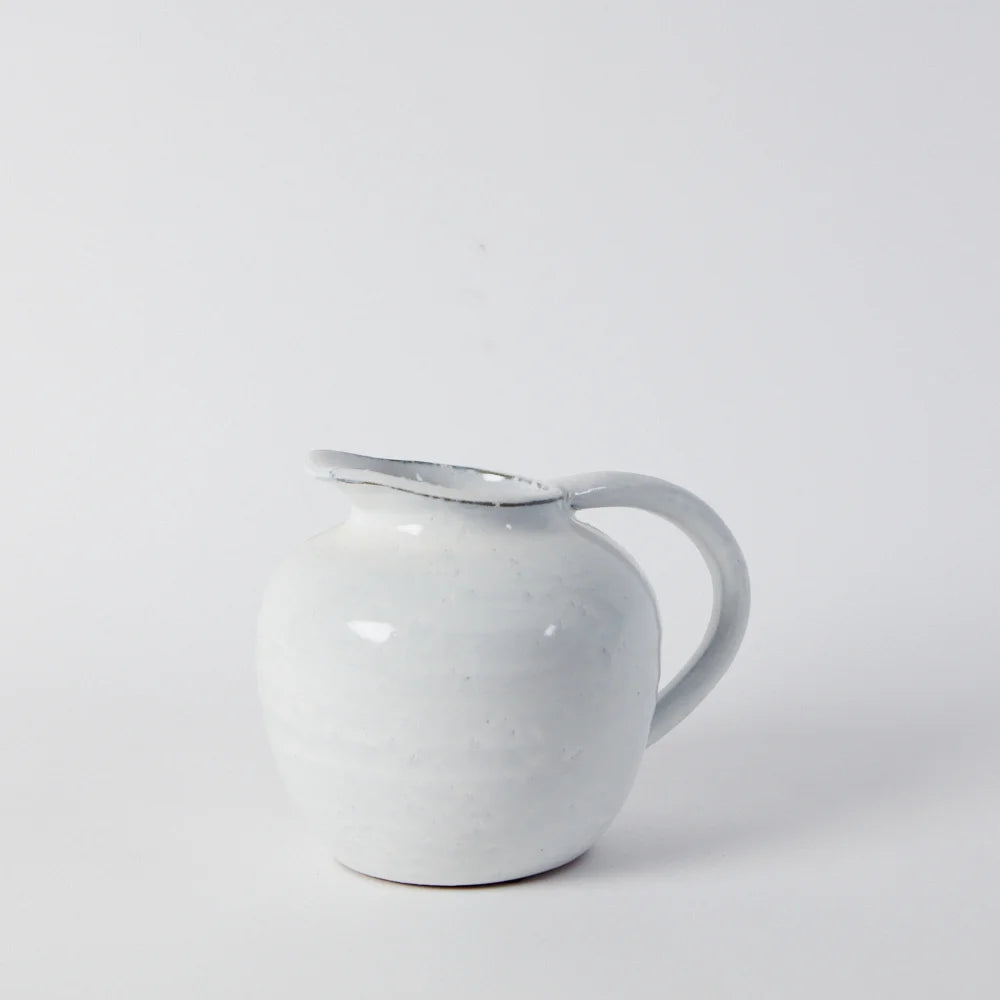 short glazed jug in white with a perfect handle shaped so it can stand against a wall with marks left by the hands that made it