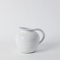 short glazed jug in white with a perfect handle shaped so it can stand against a wall with marks left by the hands that made it