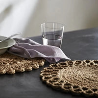 hemp placemats set apon a marble table with someone set with a bowl of breakfast and a glass of water