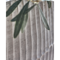 large and small ribbed cement planters by house doctor on patio