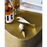 Fish bottle opener and bottle stopper set styled on a gold textured surface