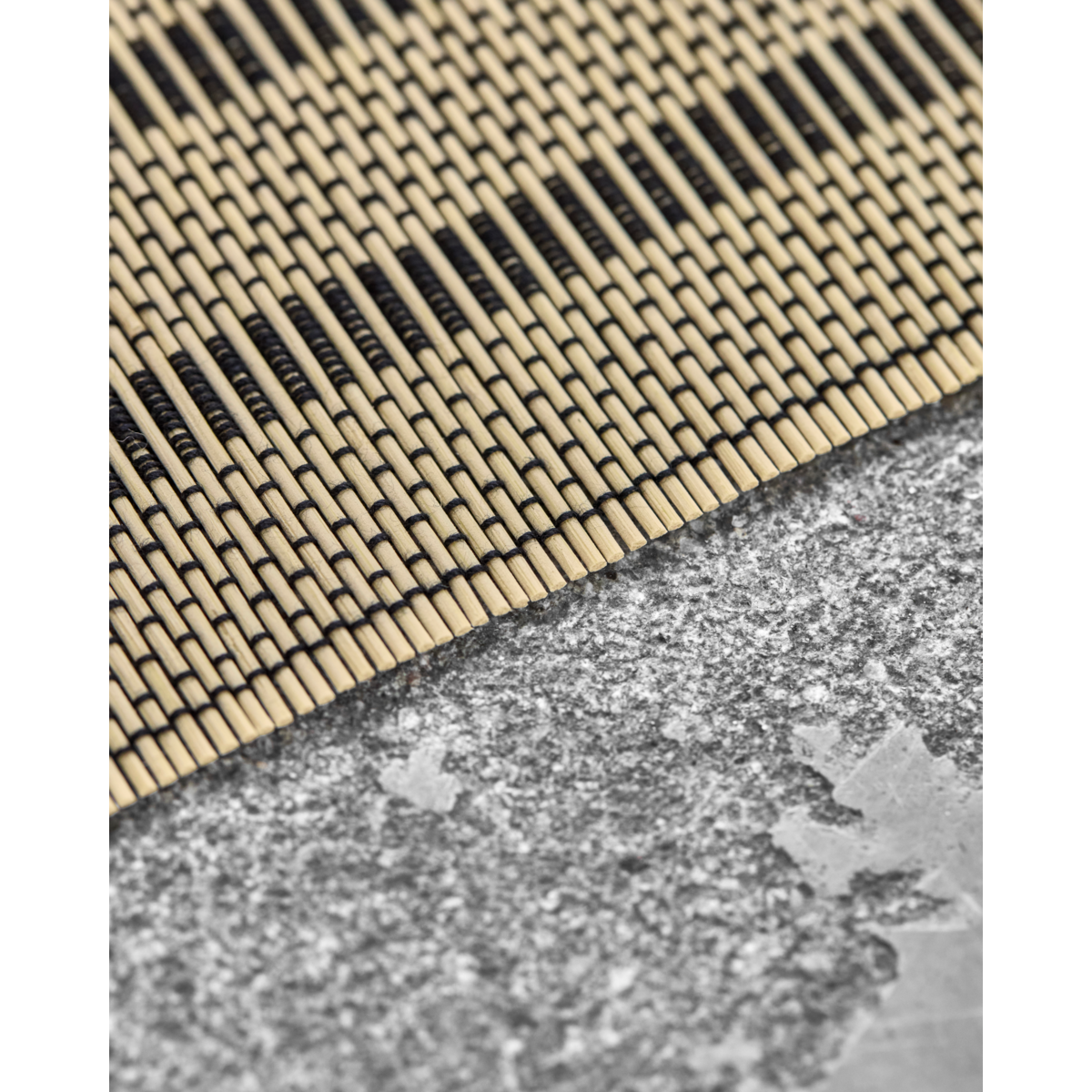 Close-up of handmade bamboo placemat edge on grey tabletop