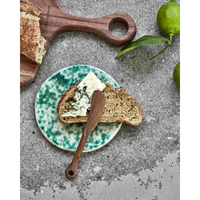 Green glazed ceramic board styled with cheese and bread
