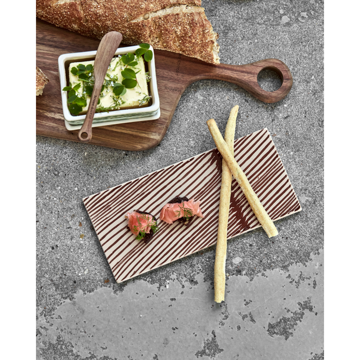 Brown ceramic board styled with salmon and breadsticks for entertaining