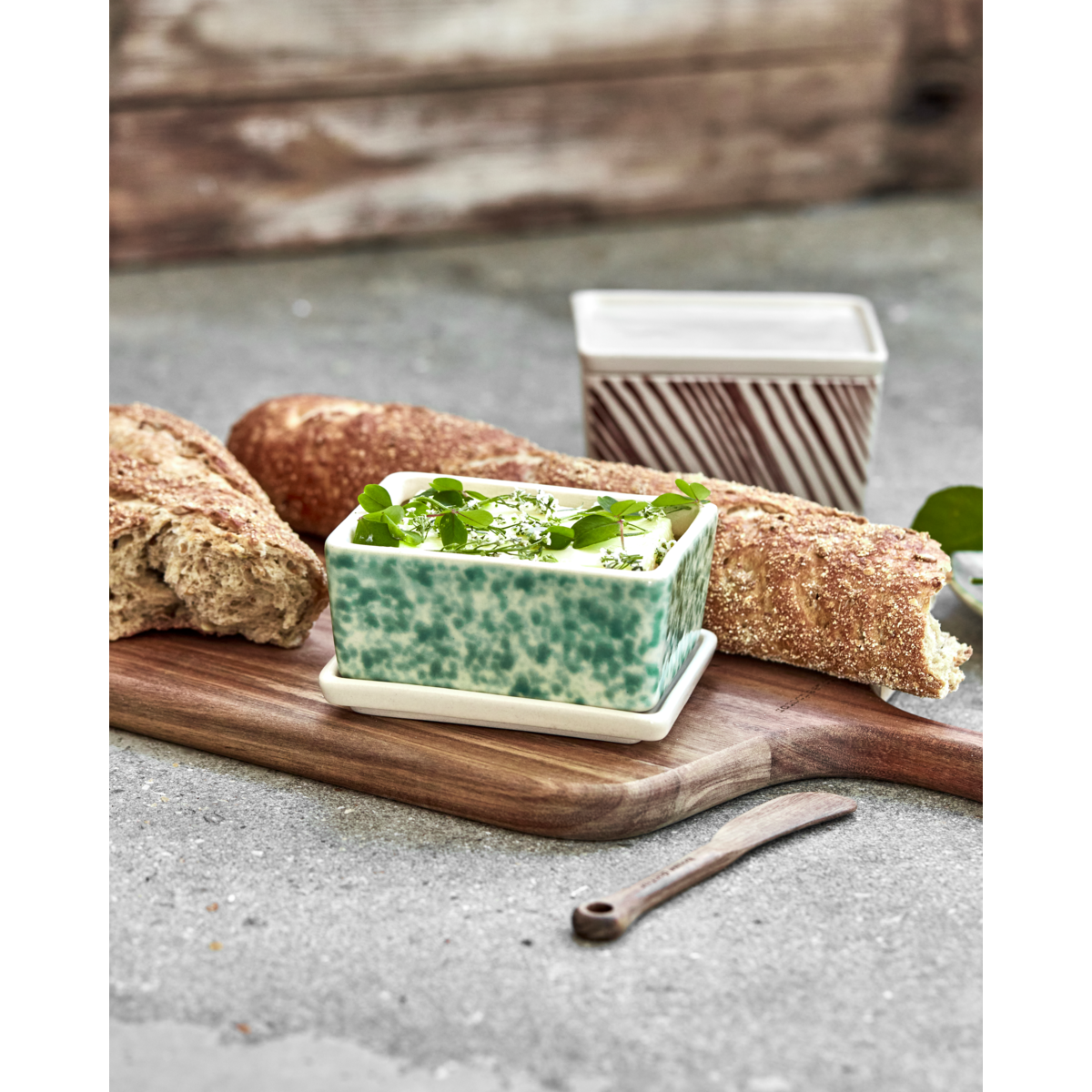 Ceramic storage box set styled with bread and butter on wooden board