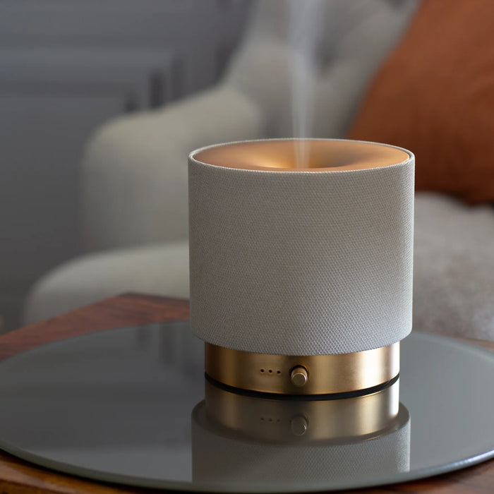 Close-up of Mira diffuser in daylight, with stone-coloured fabric and brushed gold base