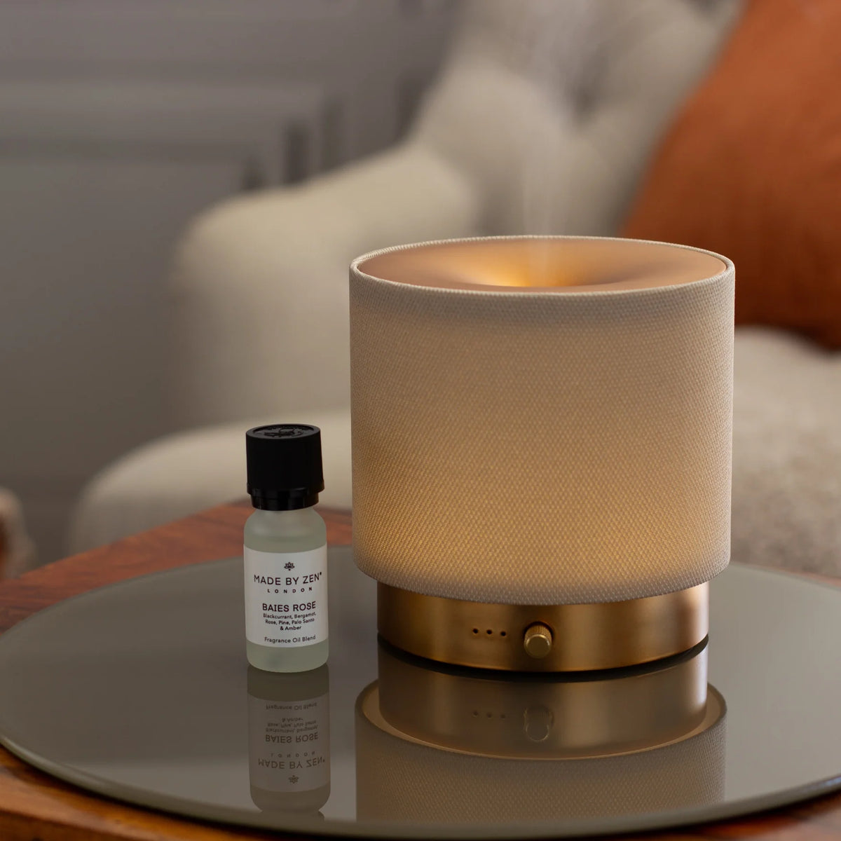 Mira diffuser by Made by Zen emitting a warm mist beside a Baies Rose fragrance oil bottle