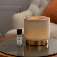 Mira diffuser by Made by Zen emitting a warm mist beside a Baies Rose fragrance oil bottle