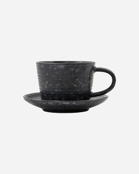 Minimalist stoneware cup and saucer in black and brown tones.