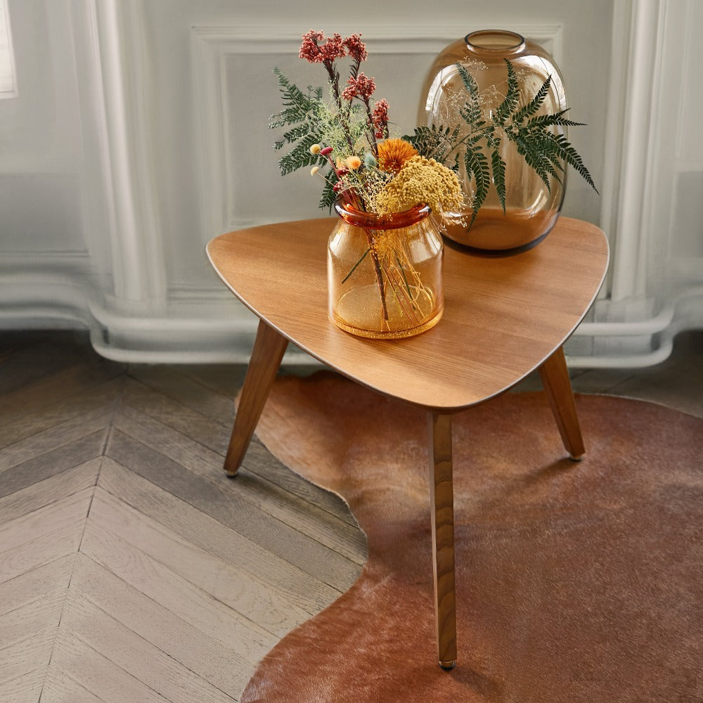 366 Concept Triangle Coffee Table styled with amber glass vases on a herringbone floor and cowhide rug