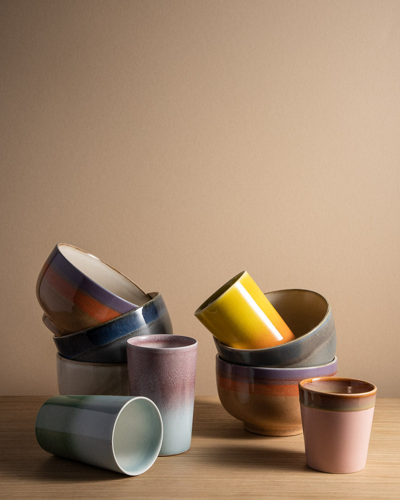 the colours of 70s collections from HKliving really stand out even when stacked together like this stack of bowls and cups with blues, yellows, pink, and grey on a light wood table