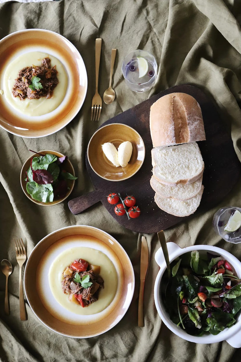 a selection of HKliving plates including from their palm collection with palm trees on them, and colourful but still subdued items from chef collection with a sunset orange, sandy yellow, and burgundy plates