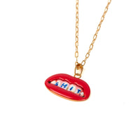 Necklace with a red lip-shaped pendant displaying the word 'SHIT' in blue on the teeth on a white background