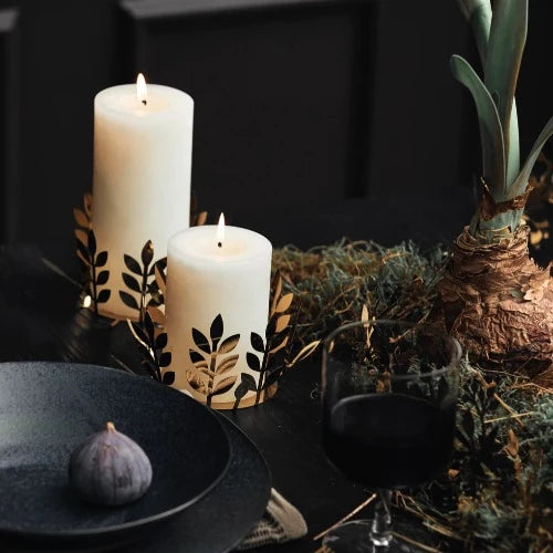 pillar canldes in a display on a table with woodland moss and a sprouting amarylis. Randomly, theres a dish with a single fresh fig net to it and nearly finished glass of red wine