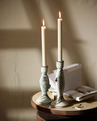 four beige taper candles standing upright on a white background, with fluted textured bases and white wicks