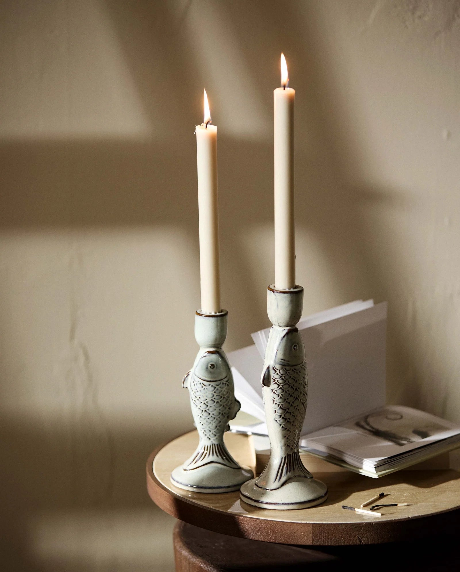 four beige taper candles standing upright on a white background, with fluted textured bases and white wicks