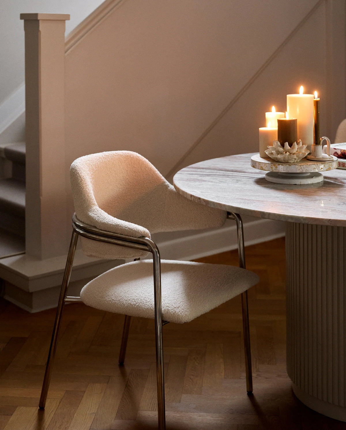 row of lit Nordal pillar candles on a white mantelpiece shelf, two tall cream candles, a shorter cream candle, two dark olive green candles of varying heights, another tall cream candle and a small dark candle, with framed artwork on the wall behind