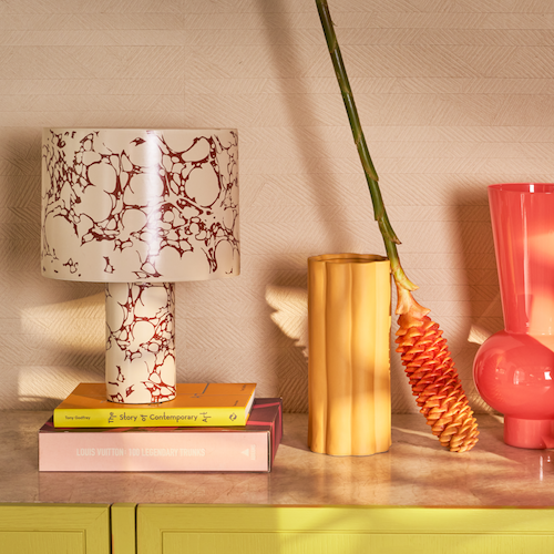 Fluido ceramic lamp styled on colourful books with warm home accessories
