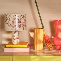 Fluido ceramic lamp styled on colourful books with warm home accessories
