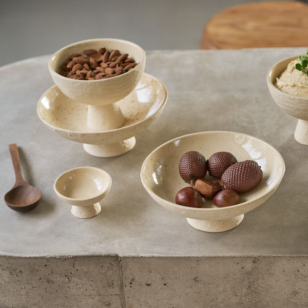 large white pedestal bowl serving fruit on a concrete table