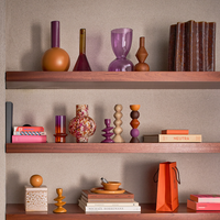 Orange and purple colour-block vase styled on a shelf with complementary decorative objects.