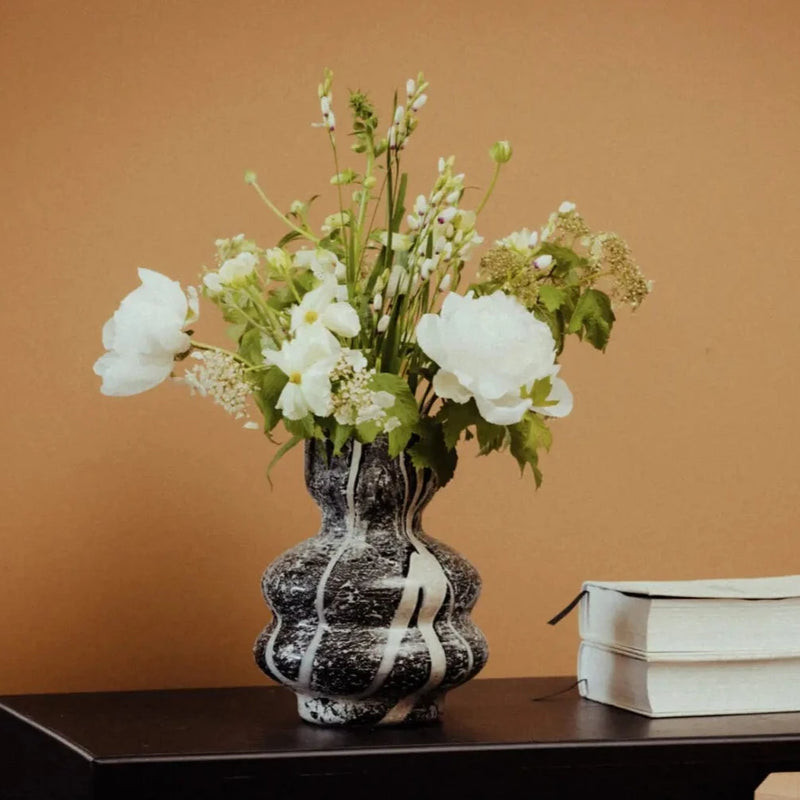 bunch of lfowers dancing out the top of a white and black marble effect hand made glass vase in nordic design from deisgn house olsson and jensen