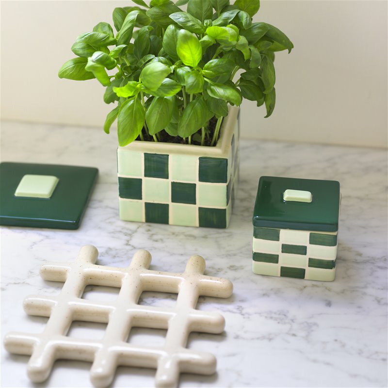 speckled ceramic trivet displayed beside green check planters on marble countertop
