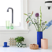 beige speckled grid trivet styled in a bright modern kitchen with plants and colourful ceramics
