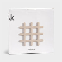 stoneware grid-shaped trivet in speckled beige shown in giftable packaging
