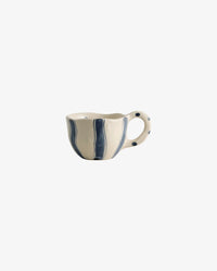 Assorted handpainted Atelier FORMA cups by Nordal displayed on a wooden shelf, including the striped GOGI cup