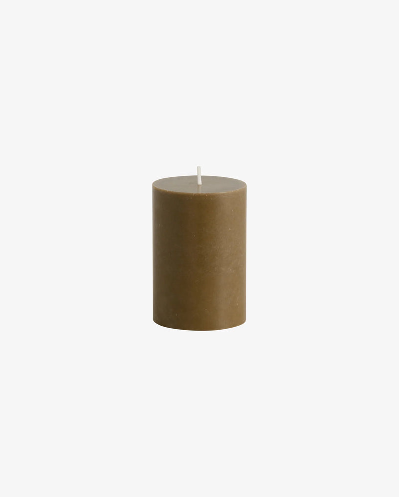 row of lit Nordal pillar candles on a white mantelpiece shelf, two tall cream candles, a shorter cream candle, two dark olive green candles of varying heights, another tall cream candle and a small dark candle, with framed artwork on the wall behind