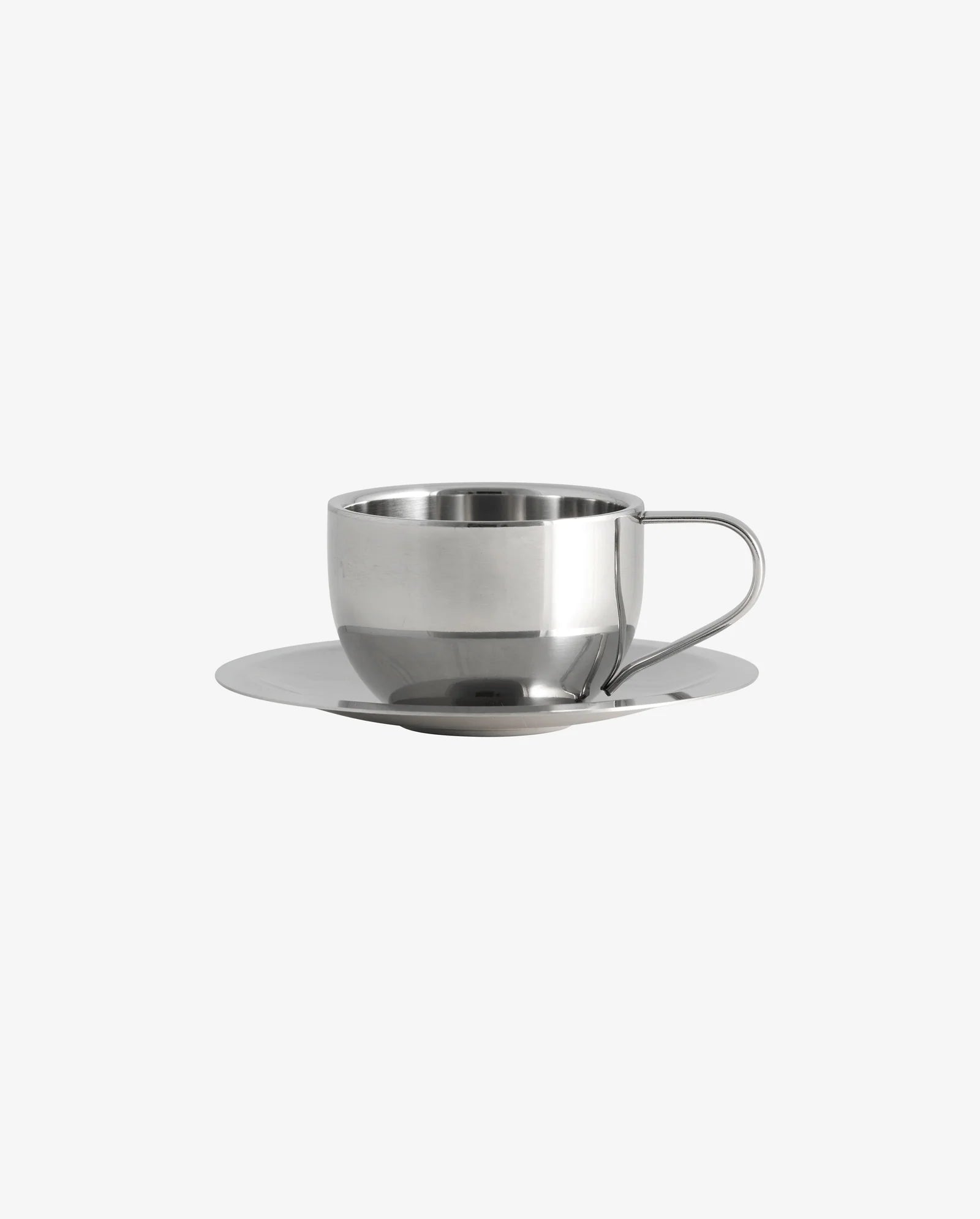 Close-up of the VIREA chrome cup and saucer by Nordal with coffee, on a dark wood table