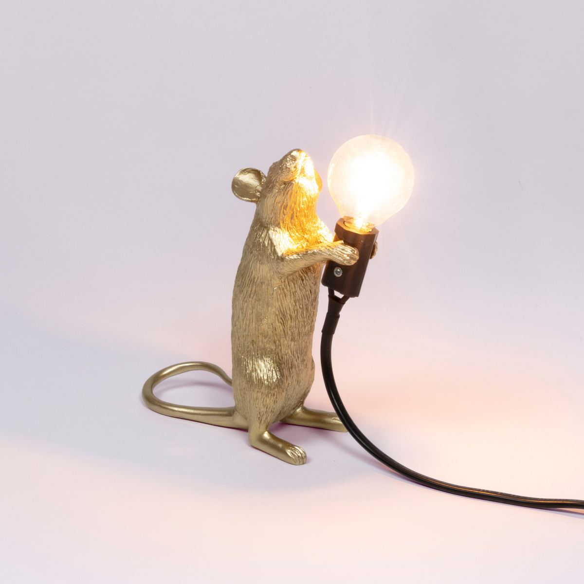 Seletti Gold standing Mouse Lamp switched on, with a warm glowing bulb