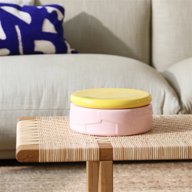 glossy pink storage jar with yellow lid styled in a modern living room by &klevering