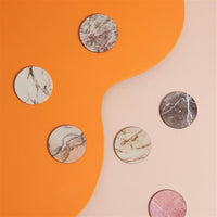 assorted marble-print coasters styled on colourful surface
