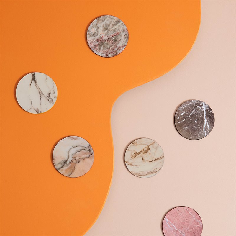 assorted marble-print coasters styled on colourful surface
