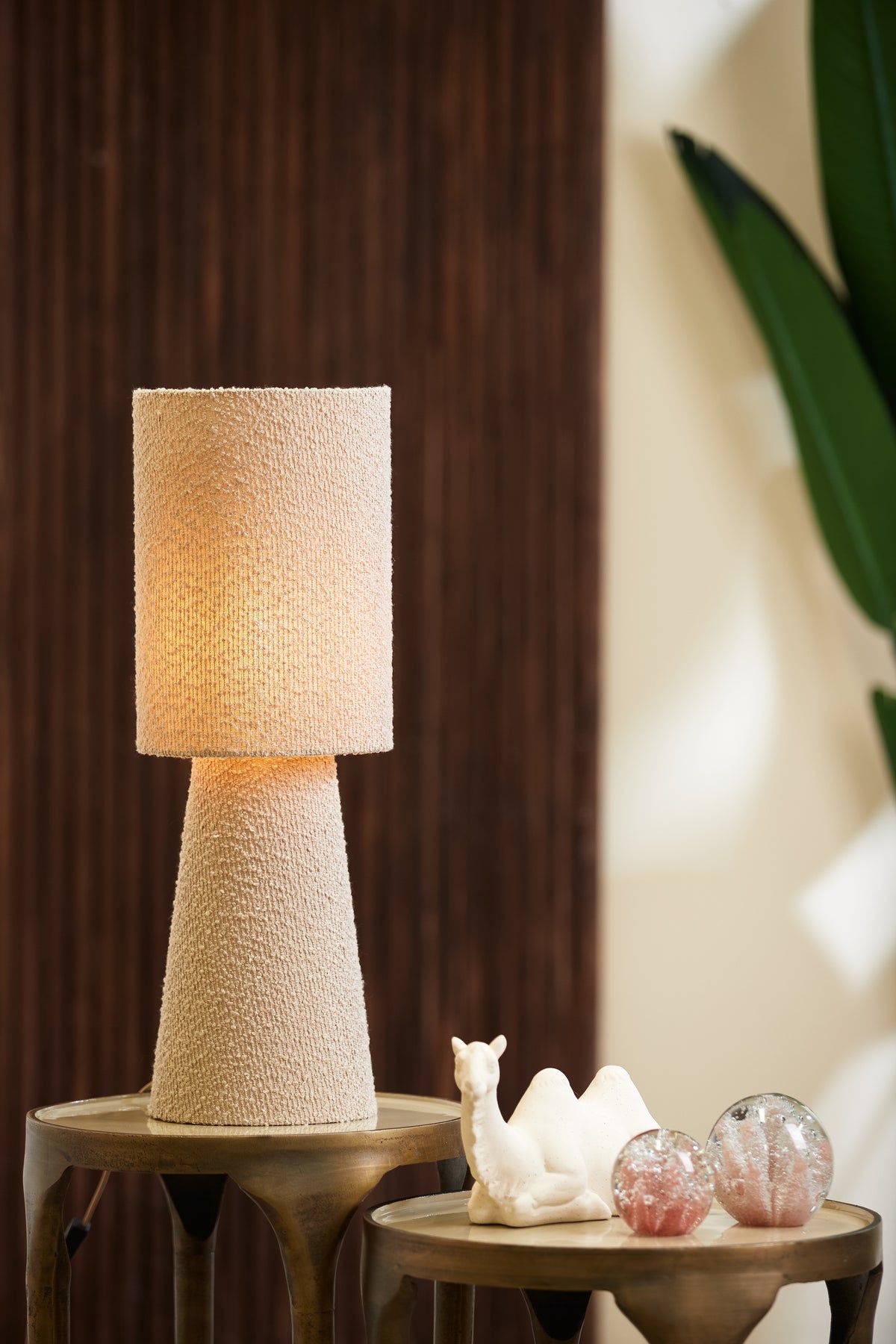sand bouclé table lamp switched on showing warm glow
