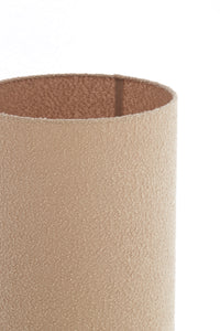 Close-up of a textured cylindrical lam shade with a brown interior on a white background