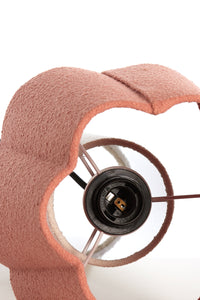 Close-up of a pink hair tie with a black circular component on a white background