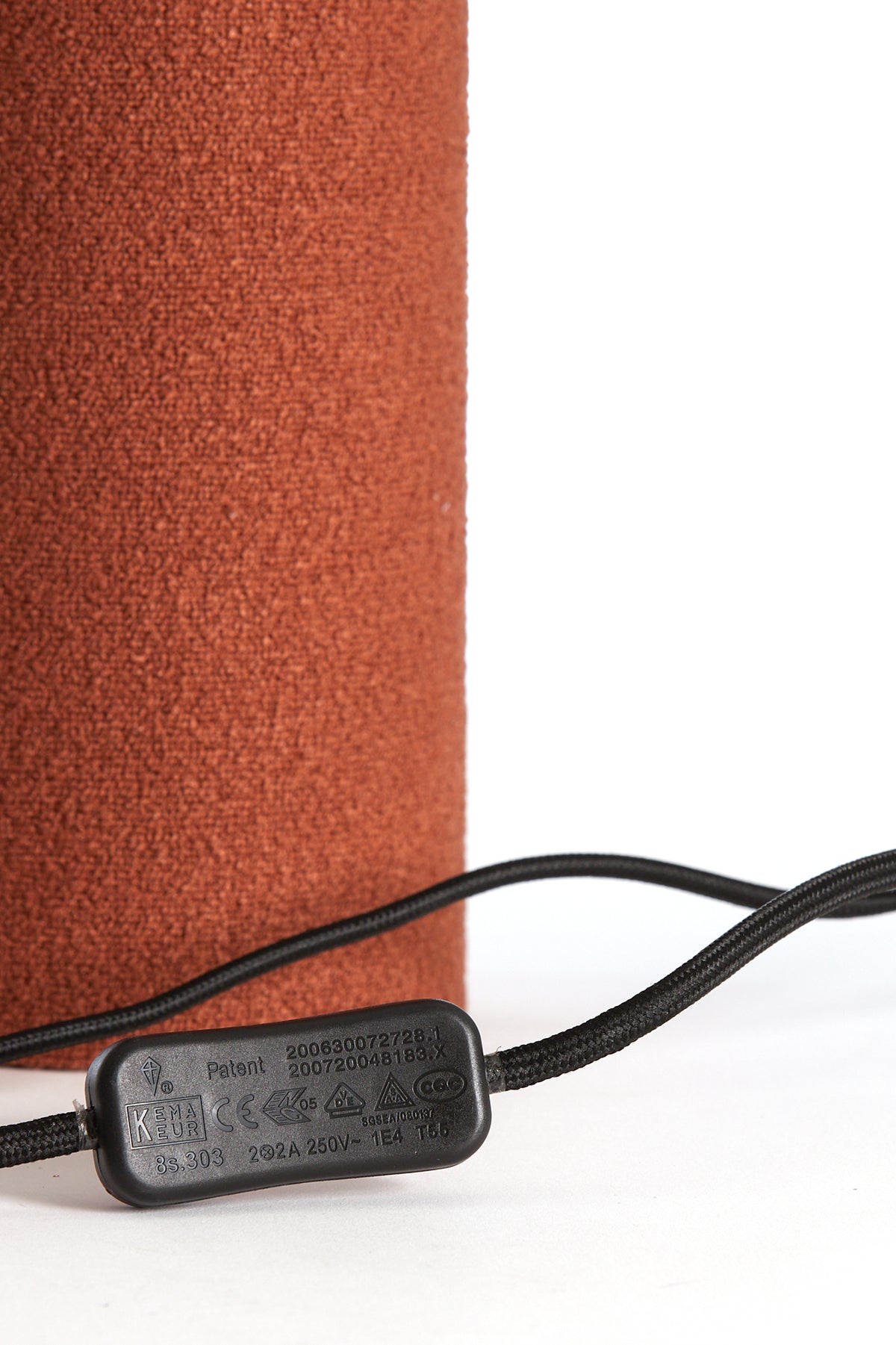 close-up of black cord and inline switch on orange textured lamp
