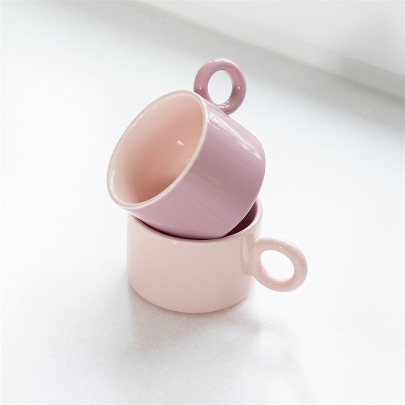 Two pink &klevering Chiquito mugs stacked on a counter in a soft-toned kitchen.