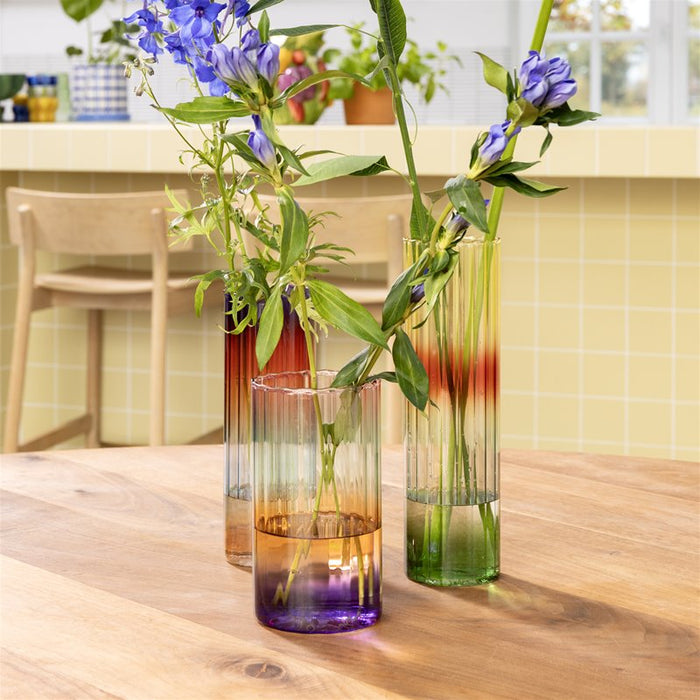 tall gradient glass vases by &k styled with flowers on a wooden table
